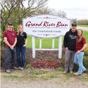 Two couples standing beside a Grand River Bean sign outdoors.