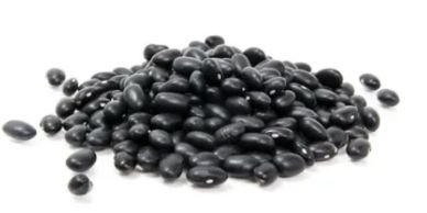 A pile of glossy black beans on a white surface.
