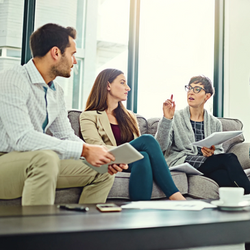 A group of people sitting on a couch having a casual meeting.