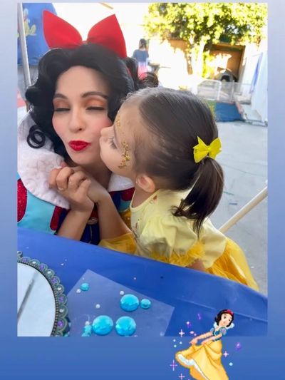 Snow White getting a kiss on the cheek by little girl and a celebration.
