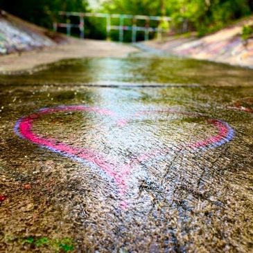 Pink heart chalk drawing on concrete pathway.