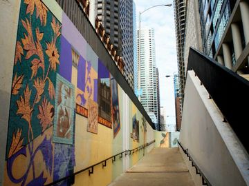 Urban walkway with colorful murals and skyscrapers.