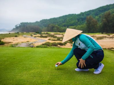 A caddie placing a golf ball on a tee in Vietnam