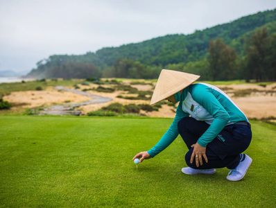 A caddie placing a golf ball on a tee in Vietnam