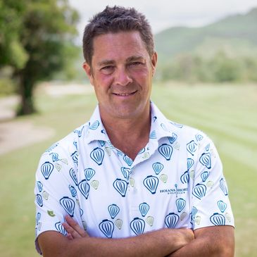 Golfer with arms crossed and golf course in the background