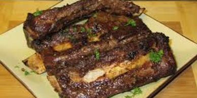 Grilled beef ribs garnished with herbs on a square plate.