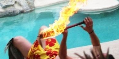 Person performing a fire-eating stunt by a pool.