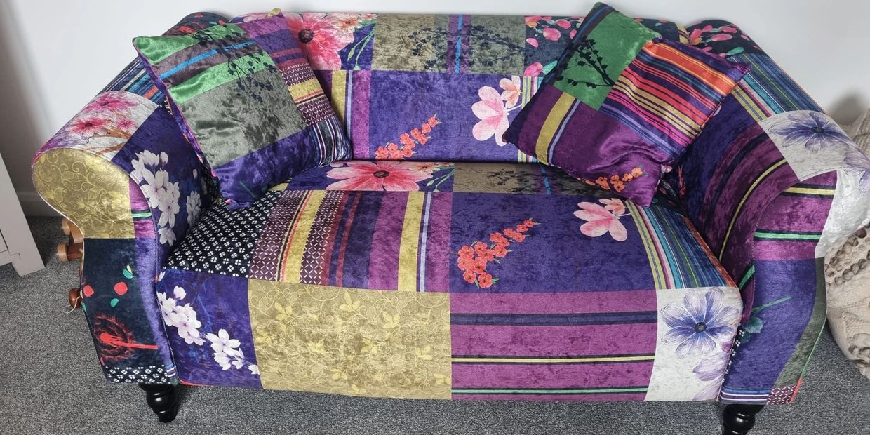 Colorful patchwork sofa with floral and striped patterns.