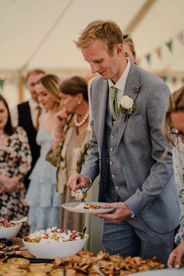 Groom serving himself at a wedding buffet catered by Ad Hoc Catering - seasonal ingredients.
