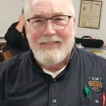 Smiling elderly man with glasses and white beard.