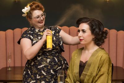 Stylist Anna is smiling while spraying the finishing touch of hairspray for her client.