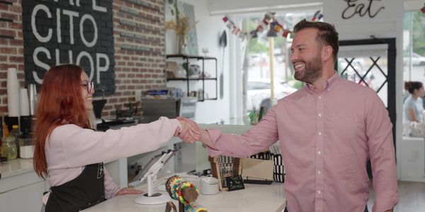 Customer and barista shaking hands in a cafe.