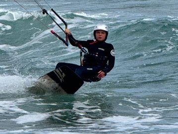 Kite surfer glides over choppy ocean waves with focus and control.