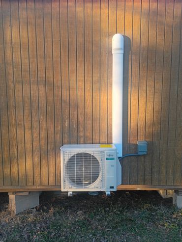 Fujitsu air conditioning unit mounted on wooden wall outdoors.