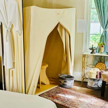 Cozy spa room with a steam tent, bathrobes, and elegant decor.