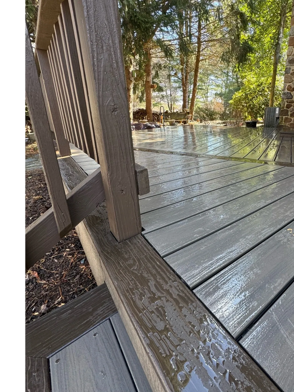 Wet wooden deck with railing on a sunny day.