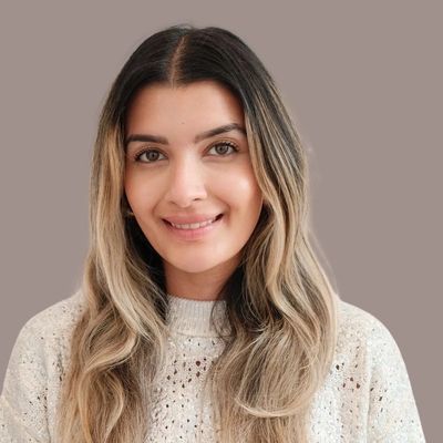 Smiling woman with long ombré hair wearing a knitted sweater.