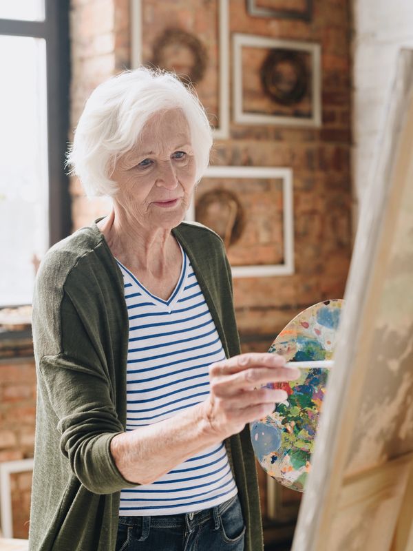 Mount Vernon Companion Care client painting at an easel, showing how she is able to age in place.