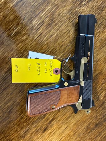 A black and wooden handgun with a yellow tag on a wooden surface.