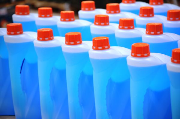 Rows of blue windshield washer fluid bottles with orange caps.