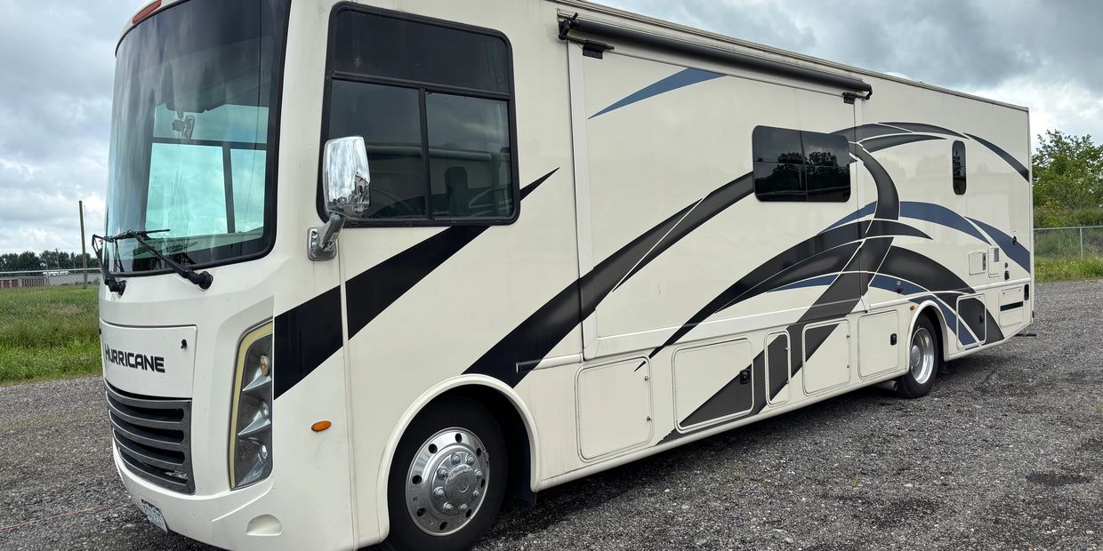 White and black Hurricane RV parked on gravel.