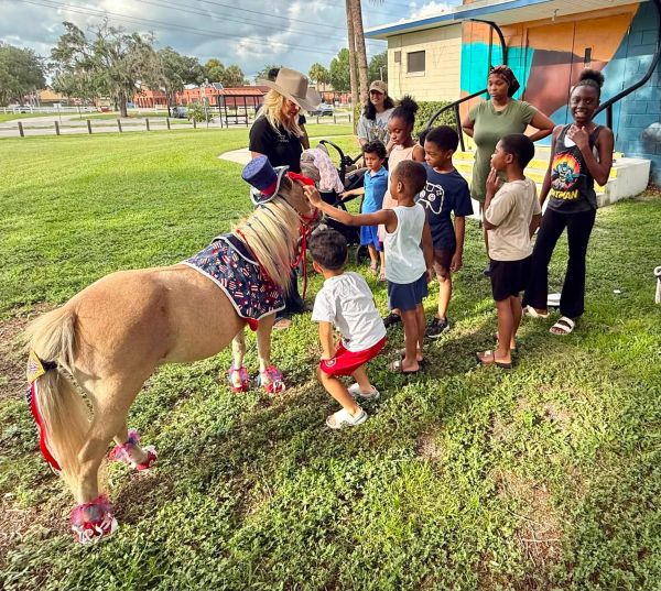 Children gather around a decorated pony outdoors.