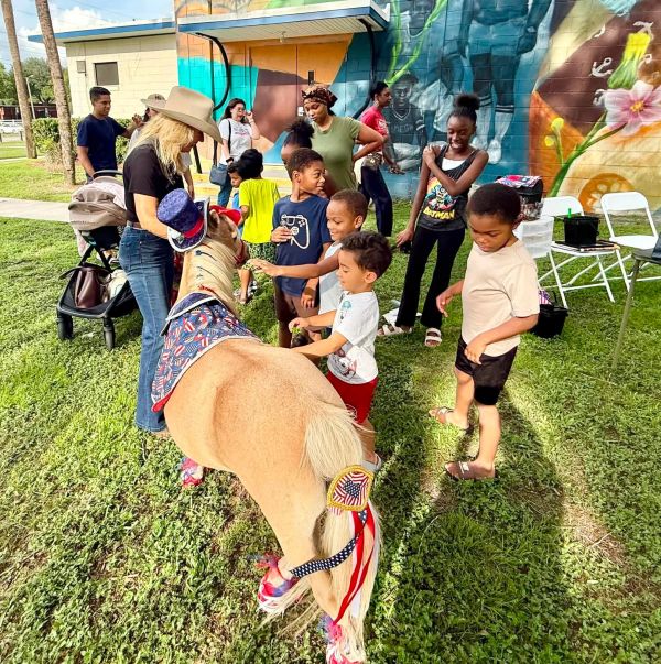Children interacting with a pony dressed in patriotic attire.