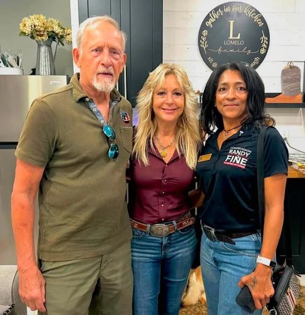 Three people posing indoors with warm smiles.