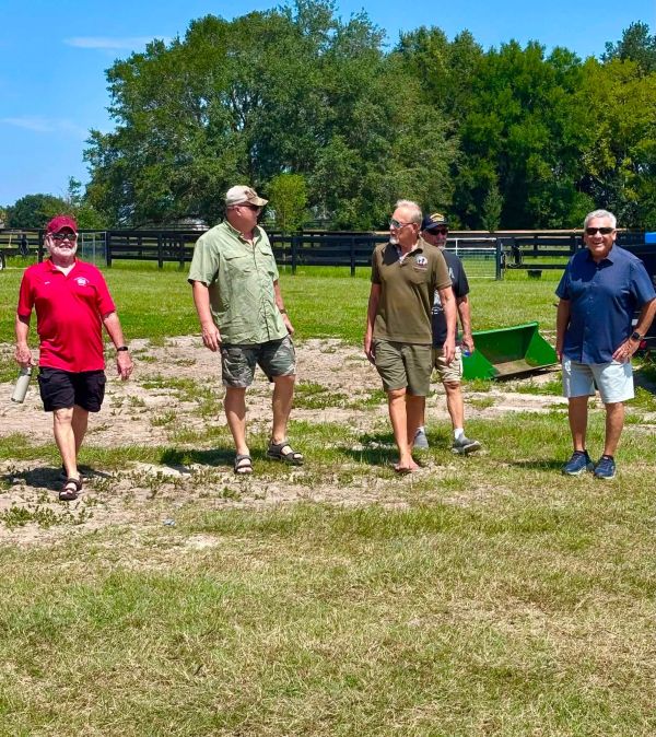Five men walking outdoors on a sunny day.