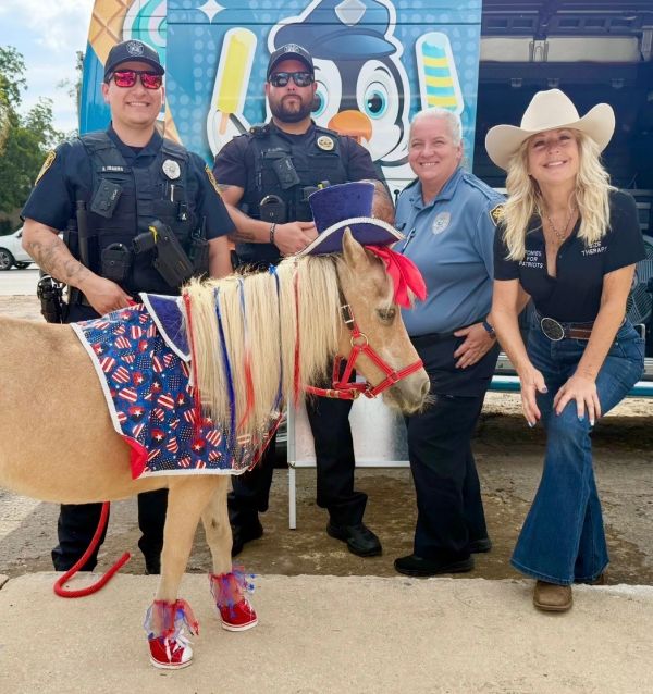 Three officers and a woman posing with a decorated horse.