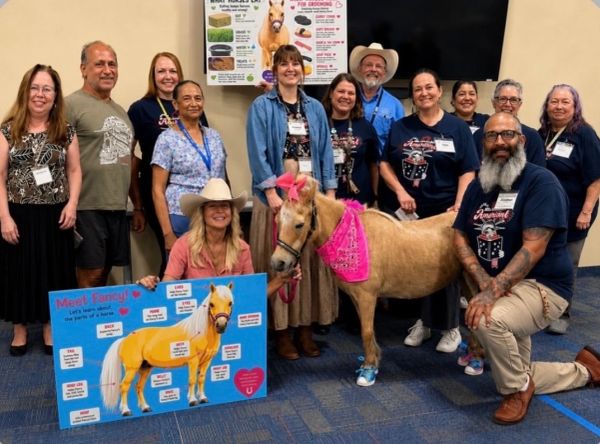 Group photo with a horse and an informational board.