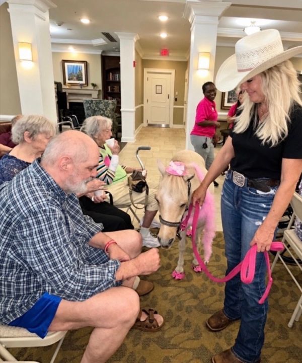 A woman and a miniature horse visiting elderly people.