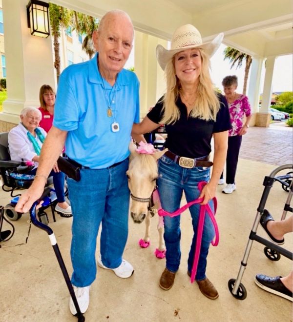 Elderly man and woman with miniature horse at a care facility.