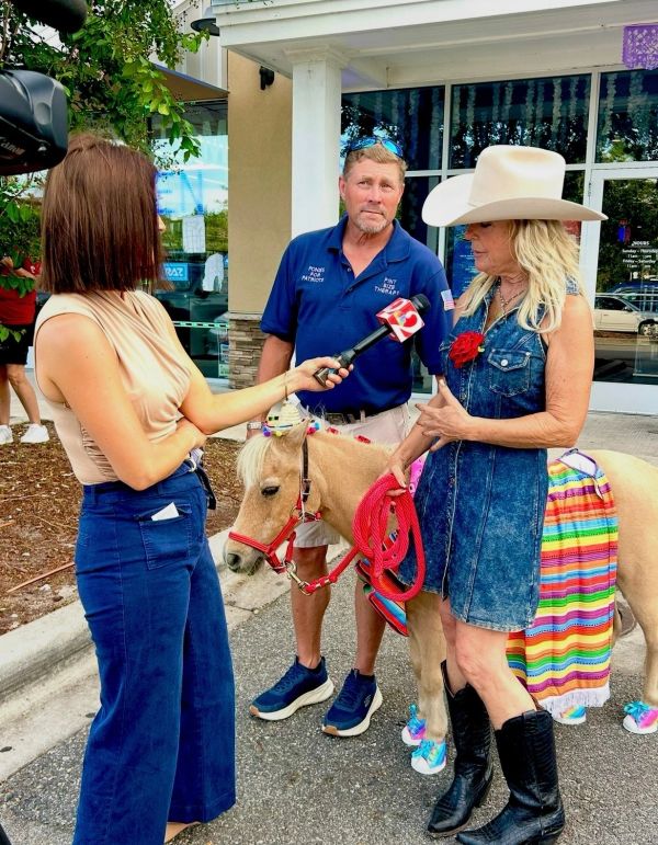 A reporter interviews a woman with a pony.