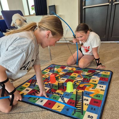Two girls playing archery Snakes & Ladders