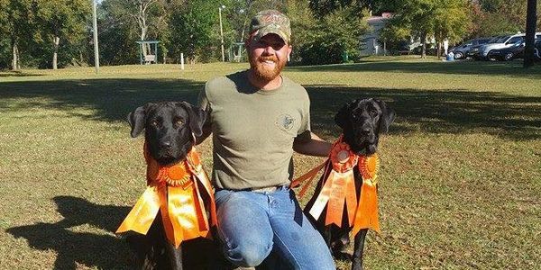 A man with two black competing dogs