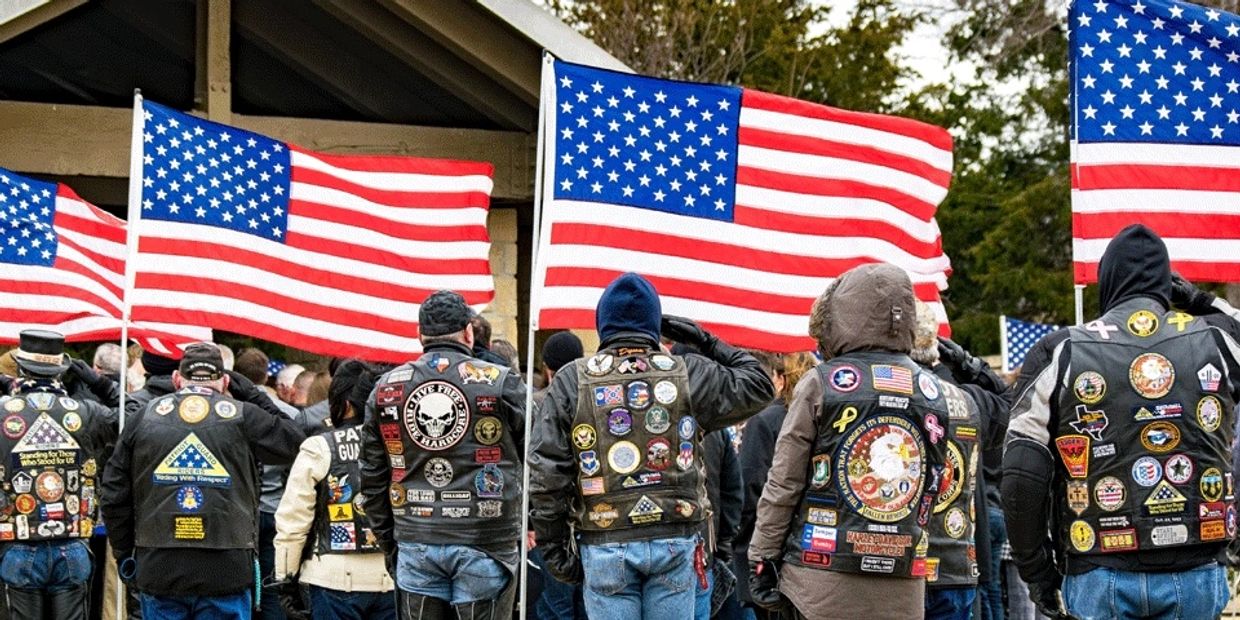 Group saluting with American flags and patched jackets.