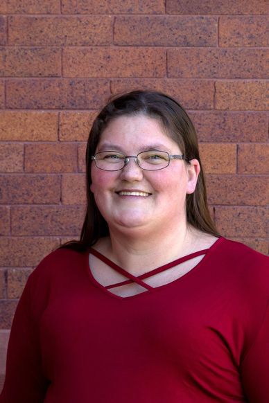 Smiling woman with glasses wearing a red top.