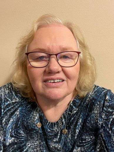 Smiling woman with glasses and curly hair.