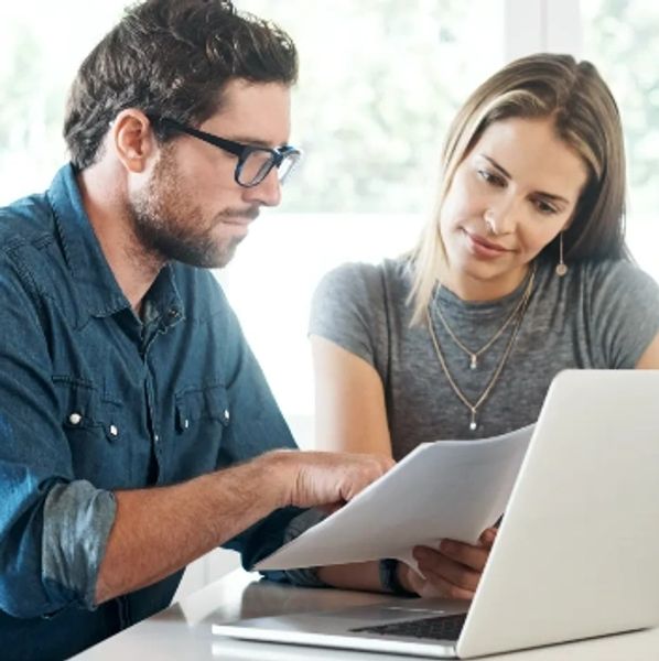 Two colleagues discussing documents with a laptop in front of them.