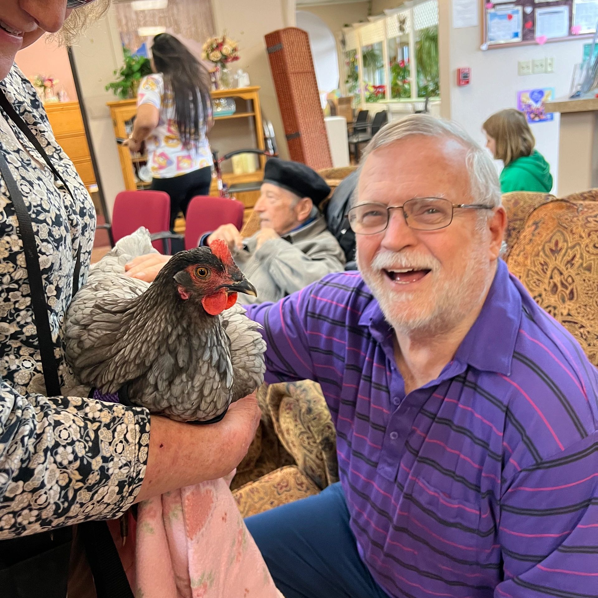Senior finds joy petting a chicken at Intergenerational Daycare in Tigard, OR.