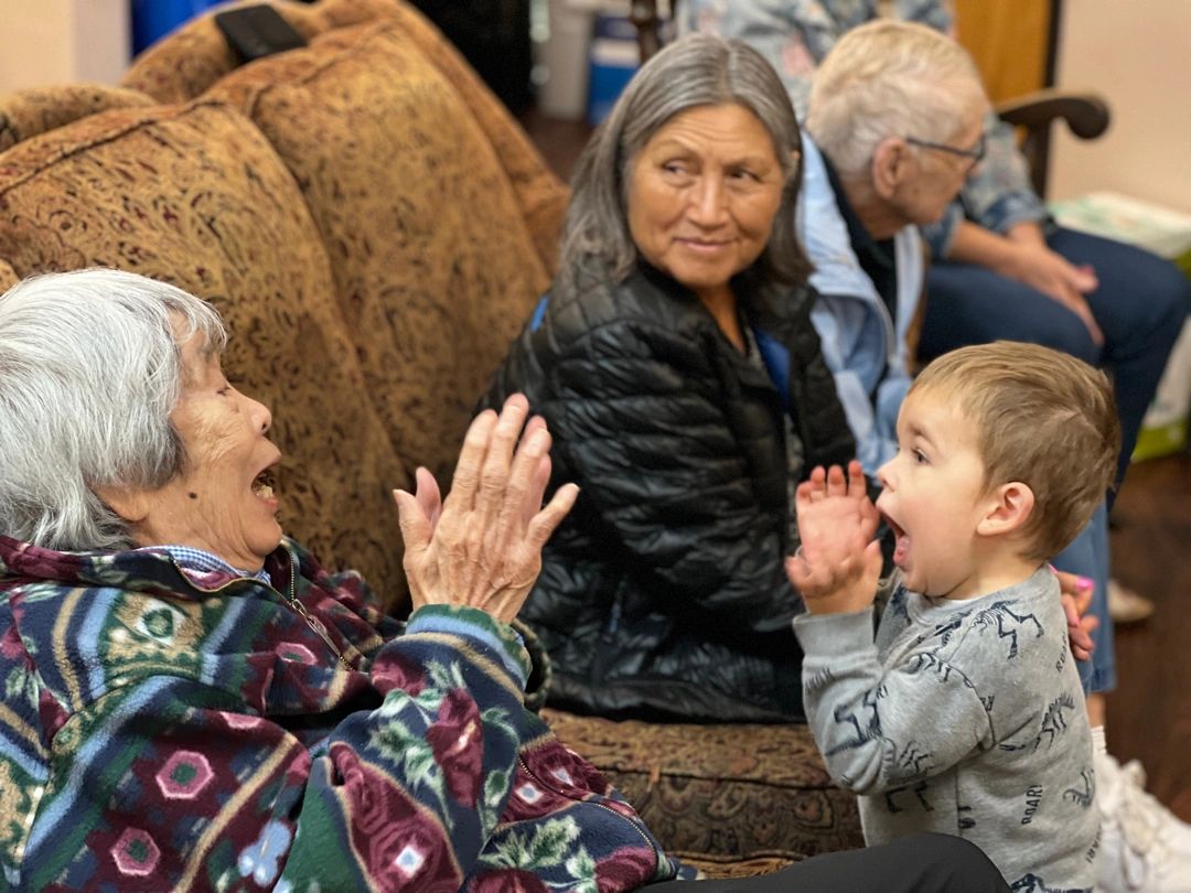 Senior woman and young boy delight in each other.