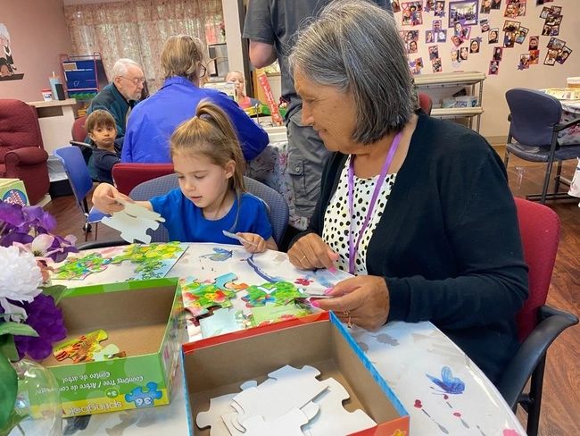 Seniors and children enjoy time together doing a puzzle at Gentog Intergenerational Adult Day Center