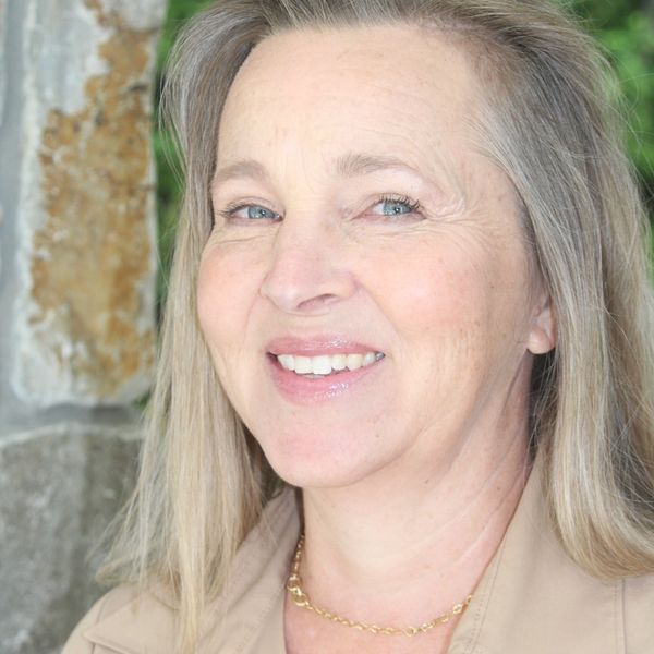 Smiling middle-aged woman with blonde hair and blue eyes.