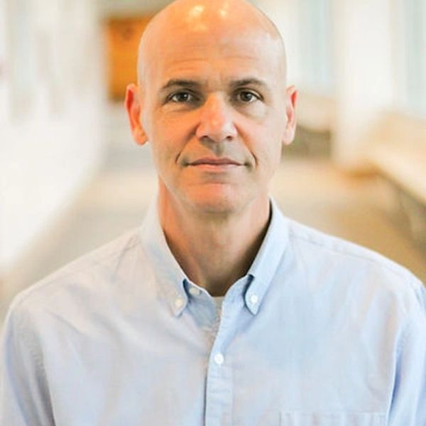 Portrait of a bald man wearing a light blue button-up shirt indoors.