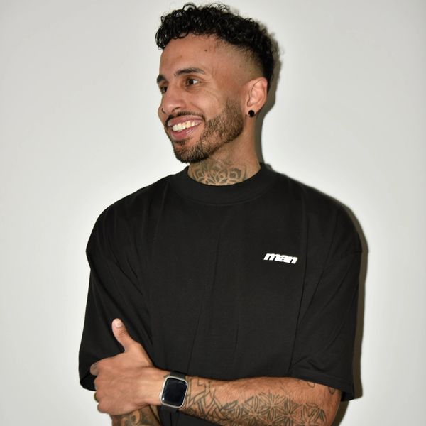 Smiling man in black t-shirt with tattoos and smartwatch.