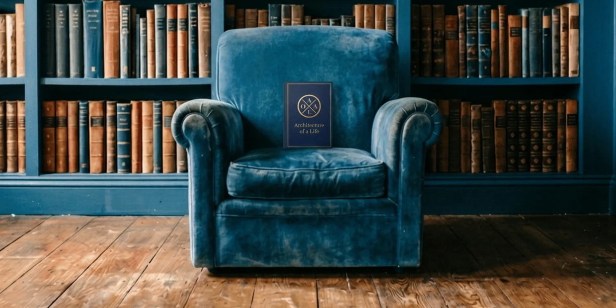 Blue velvet armchair with a book in front of a bookshelf.