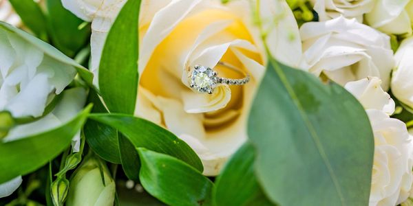 a bouquet of white roses and a wedding ring