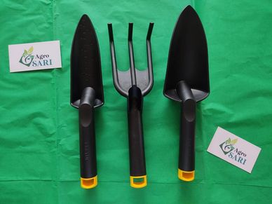 Tres herramientas de jardinería sobre tela verde.