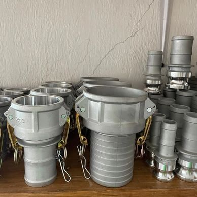 Varias conexiones industriales de metal apiladas en un estante.